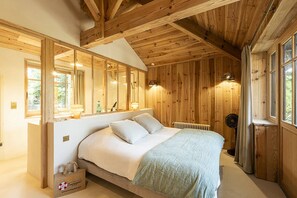 Ein Schlafzimmer mit Holzboden, einem Bett mit weißer Bettwäsche, einem Heizkörper und einem Fenster mit Vorhängen.