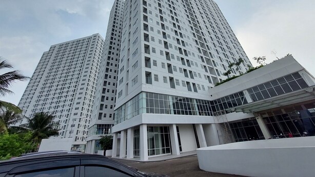 Een modern hoog gebouw met een glazen gevel en meerdere balkons.