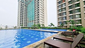 A swimming pool with lounge chairs, surrounded by high-rise residential buildings. - Elegant And Comfy 2Br Apartment Sky House Alam Sutera (Tangerang)