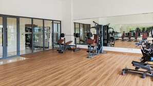 A gym with exercise equipment, large mirrors, and wooden flooring. - Warm Tone Studio At Sky House Bsd Apartment (Pagedangan)