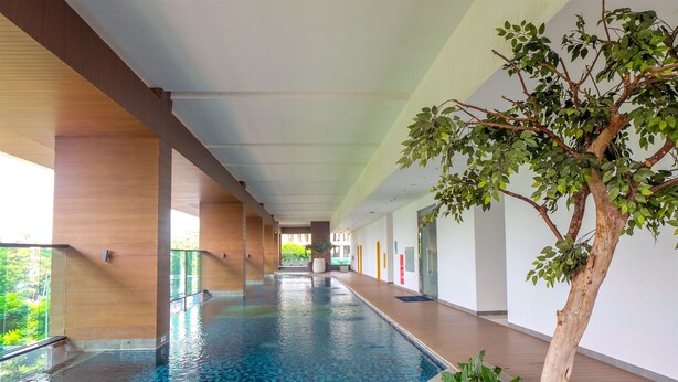 A long indoor swimming pool with a tiled floor, surrounded by wooden walls and a glass railing. - Scenic And Homey 2Br At Apartment Capitol Suites Apartment (Jakarta)