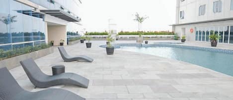 Un espace piscine aménagé sur le toit, avec des chaises longues et des plantes en pot.