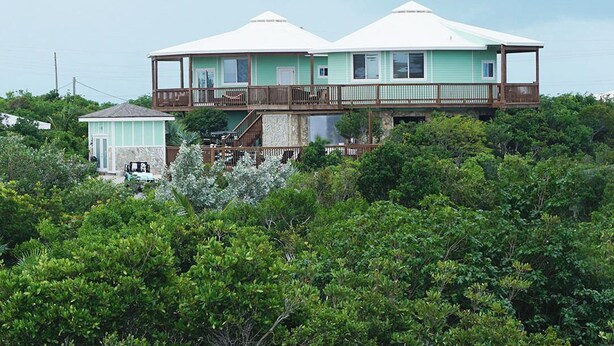 A two-story house with a balcony, surrounded by dense greenery. - Layin Low...Two Villas Offering 4 bedrooms, 2.5 baths on beautiful Staniel Cay (Staniel Cay)
