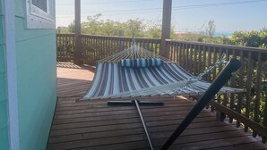 A hammock on a wooden deck with a railing, overlooking a natural landscape. - Layin Low...Two Villas Offering 4 bedrooms, 2.5 baths on beautiful Staniel Cay (Staniel Cay)