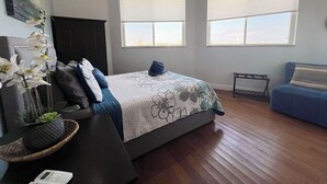 A bedroom with a bed, two windows with blinds, a ceiling fan, a dark-colored wardrobe, and a blue sofa. - Layin Low...Two Villas Offering 4 bedrooms, 2.5 baths on beautiful Staniel Cay (Staniel Cay)