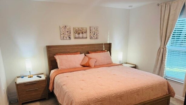Un dormitorio con una cama de madera, dos mesitas de noche y un ventanal con cortinas.