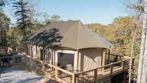 Una estructura con carpas y un patio techado, rodeada de árboles y un camino de grava.