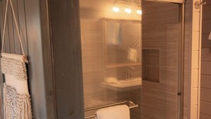 Un baño moderno con ducha de vidrio, un perchero para toallas y un inodoro a la vista.