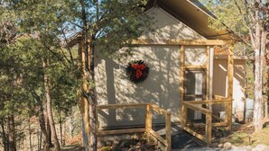 Un chalet rustique appelé «Sérénité», entouré d’arbres, avec une véranda en bois et un chemin de gravier menant à l’entrée.