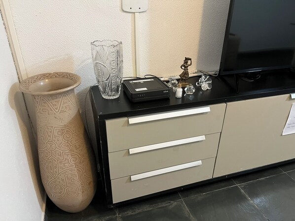 A minibar with a glass vase, a small figurine, and a remote control.