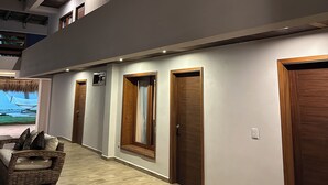 Un vaste hall d’entrée doté de portes en bois et d’un haut plafond avec des poutres apparentes.