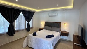 Une chambre moderne avec un grand lit, des tables de chevet, un téléviseur et un appareil de climatisation.