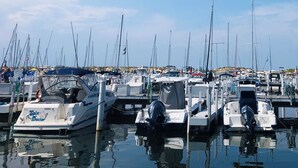 Un puerto deportivo con varias embarcaciones amarradas, agua tranquila y cielo despejado.