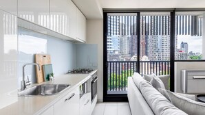 Une cuisine moderne dotée d’une grande fenêtre, d’un balcon et offrant une vue sur les immeubles de la ville.