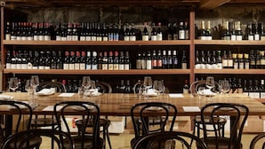 Une cave à vin avec de nombreuses étagères remplies de bouteilles de vin et une longue table entourée de chaises et de verres à vin.