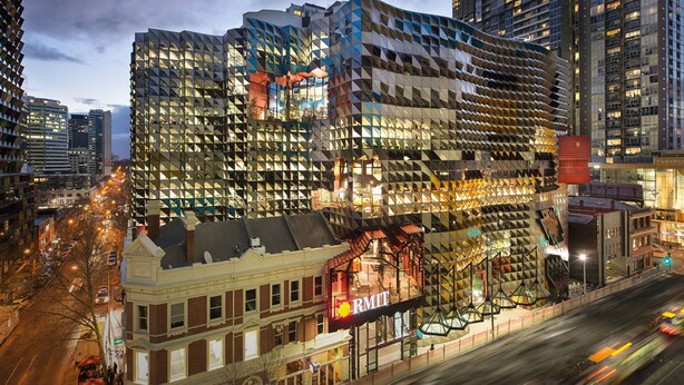 Un hôtel moderne à la façade géométrique originale, avec un panneau « RMIT » bien visible, et offrant une vue sur le paysage urbain environnant.