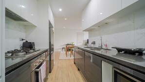 A modern kitchen with a central island, stainless steel appliances, and a wooden dining table.