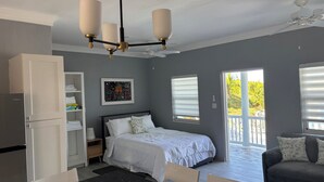 A bedroom with a bed, a nightstand, a dresser, a ceiling fan, and a window with blinds. - Brand New Apartment in George (George Town)