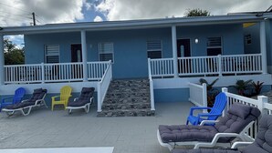 A blue building with a pool, outdoor seating, and a stone staircase. - Brand New Apartment in George (George Town)
