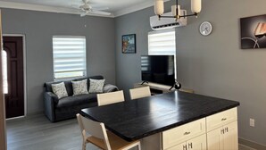 A modern kitchen with a black countertop, white cabinets, and a ceiling fan. - Brand New Apartment in George (George Town)