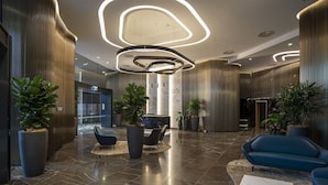 Una hall moderna con pavimento in marmo, zone relax e ampie piante in vaso.