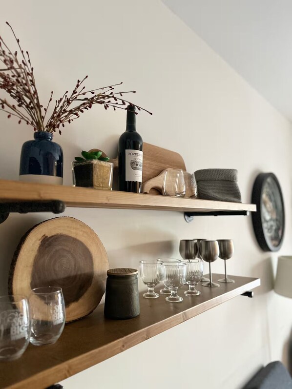 Een houten plank met een fles wijn, glazen en decoratieve objecten.