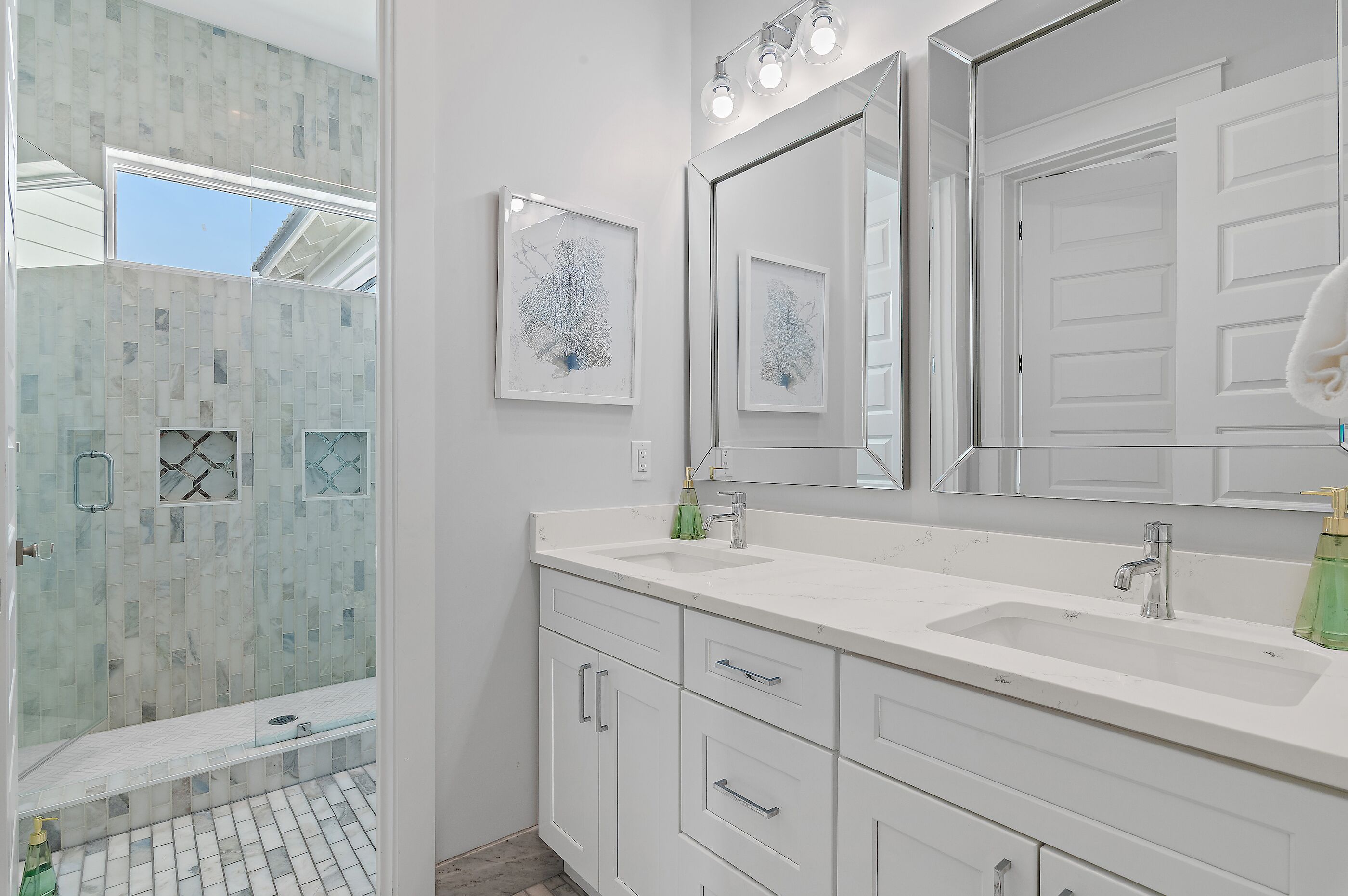 A bathroom with a white vanity, a large mirror, and a shower area with glass doors.