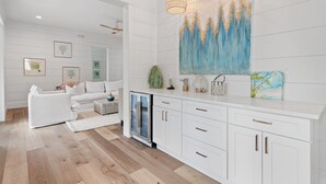 A modern kitchen with white cabinetry, a built-in refrigerator, and a large painting on the wall. - 6BR 30A Oasis • Pool, Golf Cart & Bikes (Seagrove Beach)