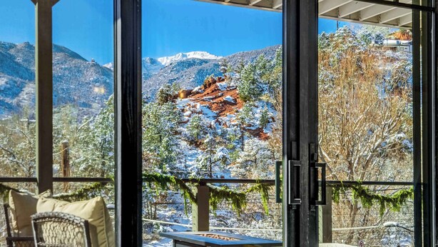 Quarto com uma grande janela com vista para uma paisagem montanhosa coberta de neve.