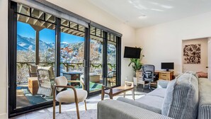 Sala de estar moderna com uma grande porta de vidro deslizante que dá para uma varanda com vista para as montanhas.