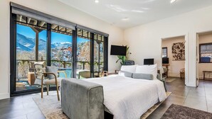 Quarto com cama grande, televisão e vista para montanhas.