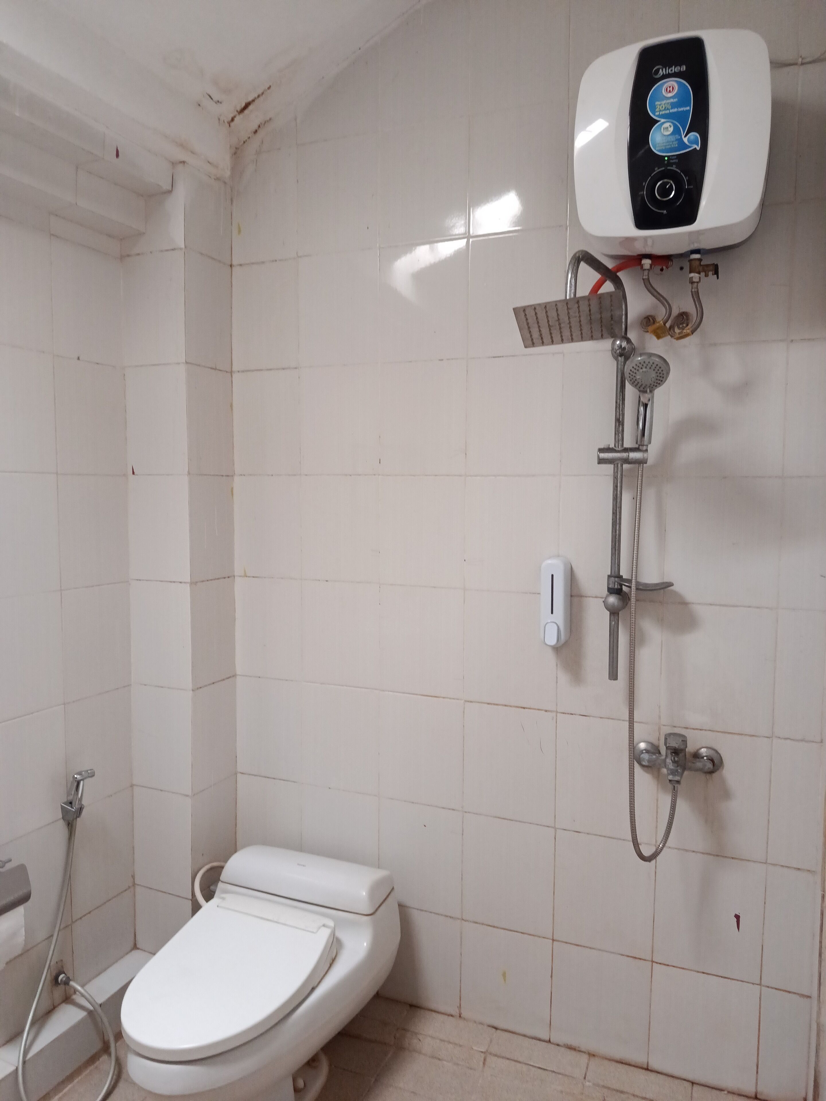 Une petite salle de bain comprenant des toilettes, une douche et un chauffe-eau.