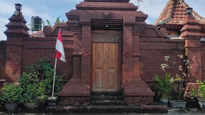A traditional brick building with a wooden door, surrounded by potted plants. - GRHA PAWITRA TROWULAN (Bejijong)
