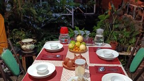 A table set outdoors with plates, bowls, a teapot, and a fruit bowl. - GRHA PAWITRA TROWULAN (Bejijong)