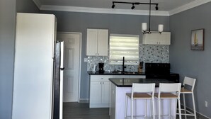 A modern kitchen with a central island, white cabinetry, and a large refrigerator.