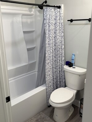 Une salle de bain avec une douche, des toilettes et un porte-serviettes.