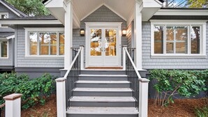 A house with a front porch, a staircase leading to the entrance, and a small garden area. - Expansive Vanderhorst 6Bd Home-- 81 Wax Myrtle (Kiawah Island)