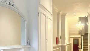 Um corredor com lareira, espelho e lustre.