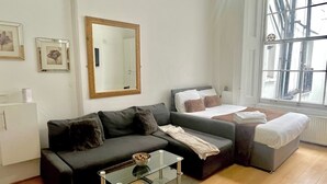 Ein modernes Schlafzimmer mit einem Bett, einer Couch, einem Glastisch und einem großen Fenster.