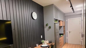 Una cocina compacta con una mesa de comedor de madera, un refrigerador y un reloj en la pared.