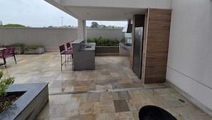 Terraza en la azotea con área de cocina, asientos y vista panorámica de la ciudad.
