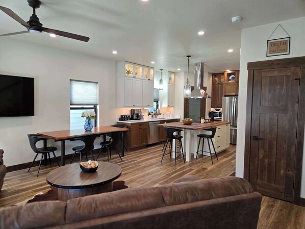 A modern kitchen with white cabinets, a wooden island, and bar stools. - The Riverlight 3 Bedroom Townhouse (Helena)