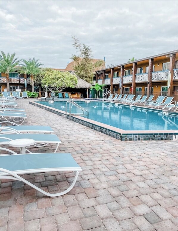 A pool area with lounge chairs and a building with balconies. - Westgate Lake Resort & Spa  (Orlando)