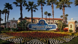 A sign for Westgate Lakes Resort & Spa surrounded by palm trees and a flower garden. - Westgate Lake Resort & Spa (Orlando)