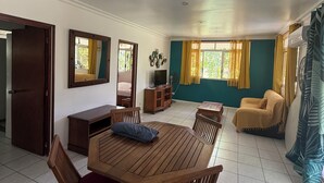 Una habitación con una mesa de comedor de madera, sillas, un sofá, un televisor y un armario.