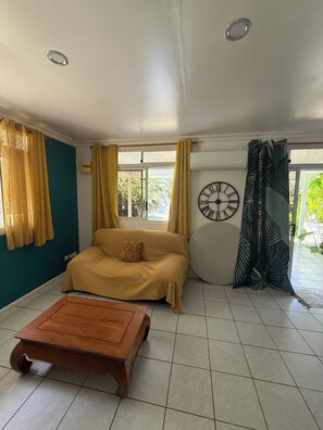 Una sala de estar con un sofá, una mesa de centro de madera, un reloj de pared y cortinas.