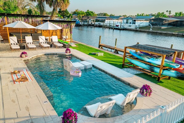 A swimming pool with lounge chairs, a hot tub, and canoes. - The Don | Fully Loaded Waterfront Wellness (Tampa)
