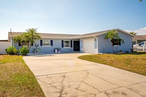 A single-story house with a front entrance, a driveway, and a small lawn with a palm tree. - The Don | Fully Loaded Waterfront Wellness (Tampa)