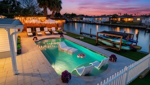 A swimming pool with lounge chairs and a dock with kayaks. - The Don | Fully Loaded Waterfront Wellness (Tampa)
