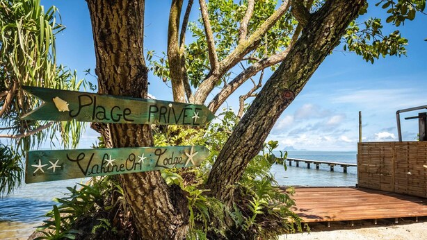 Un árbol con letreros de madera que indican 'Plage Privé' y el Lodge 'Valerie Or'.